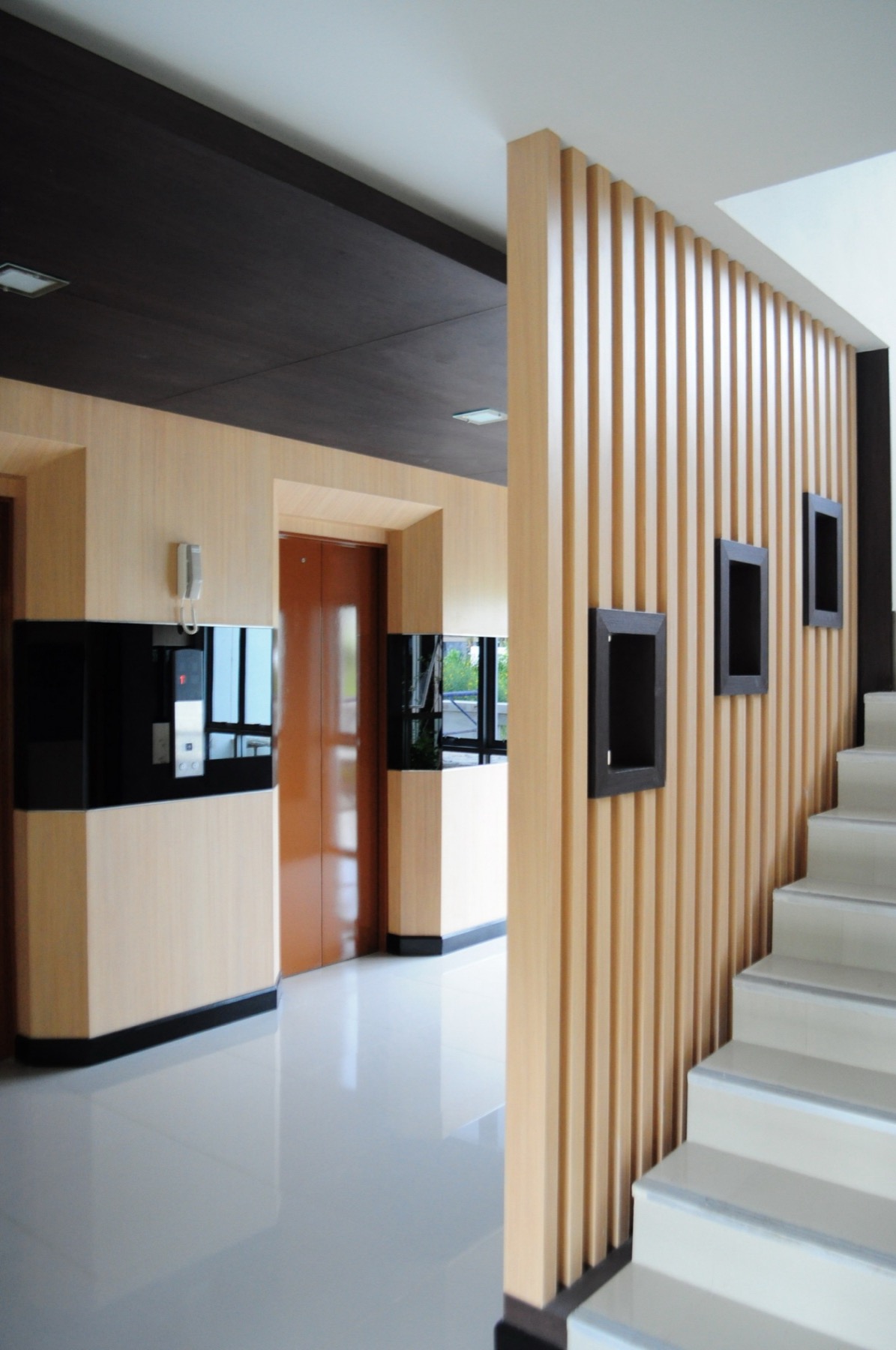 Passenger lift hall with stairs and a wood-slat feature wall