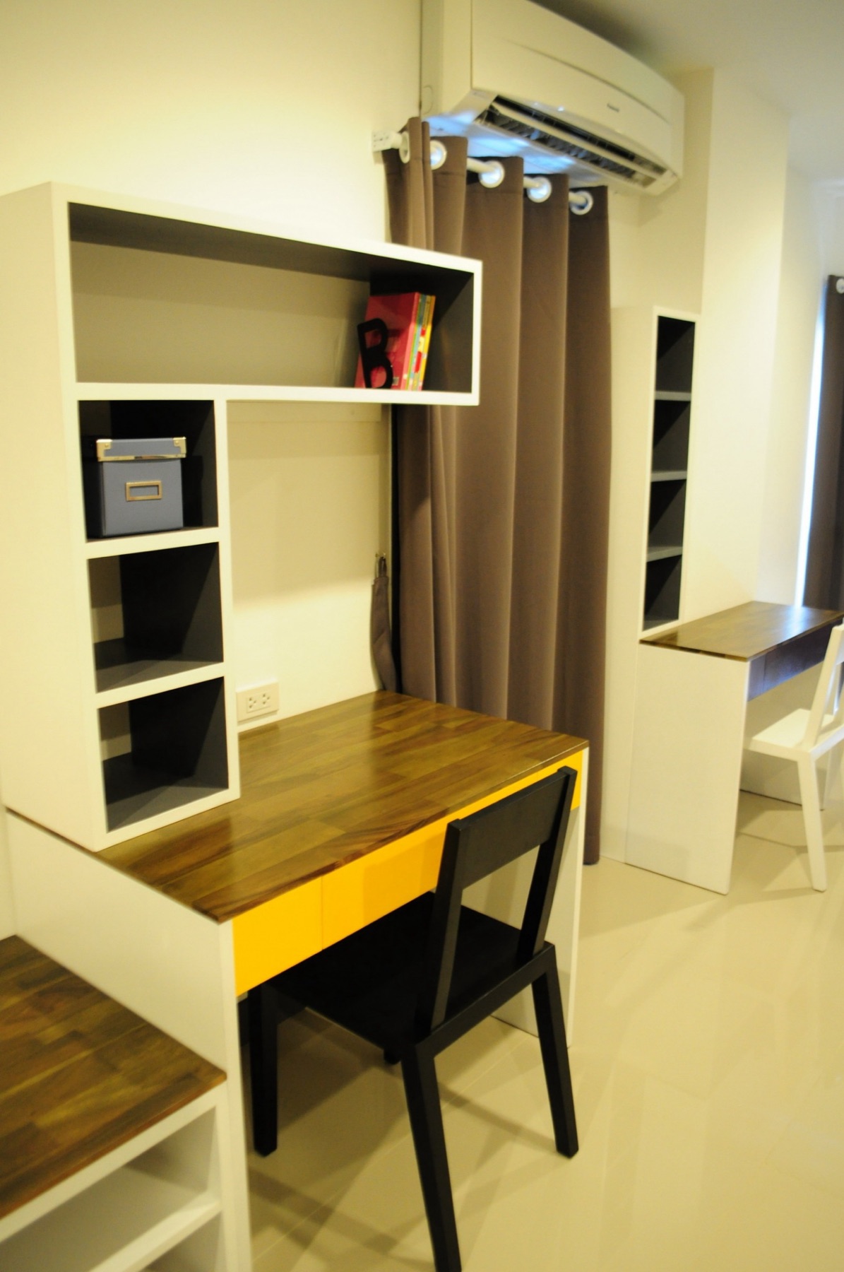 Two work desks, shelving, and storage inside the Deluxe room